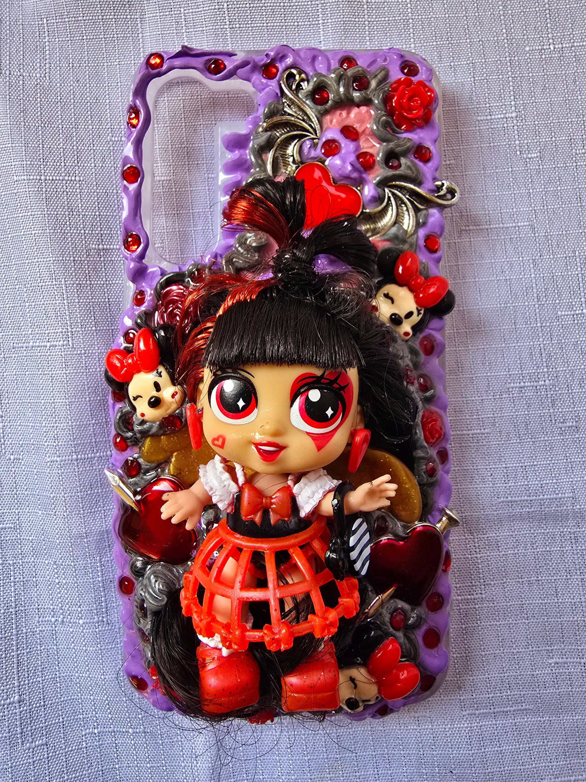 Handmade Samsung S23 Plus phone case with gothic and doll-inspired design, featuring red and black accents, heart charms, and 3D figure on a purple base.