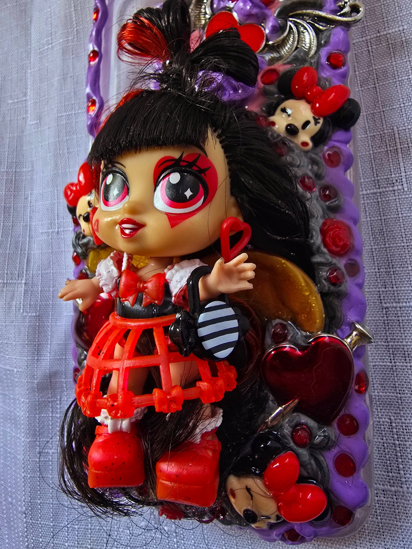Handmade Samsung S23 Plus phone case with gothic and doll-inspired design, featuring red and black accents, heart charms, and 3D figure on a purple base.