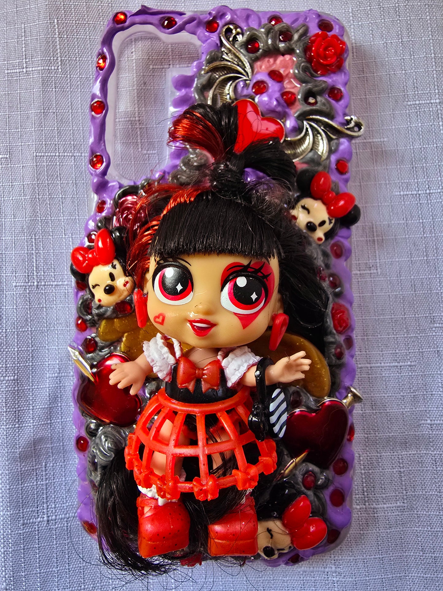 Handmade Samsung S23 Plus phone case with gothic and doll-inspired design, featuring red and black accents, heart charms, and 3D figure on a purple base.