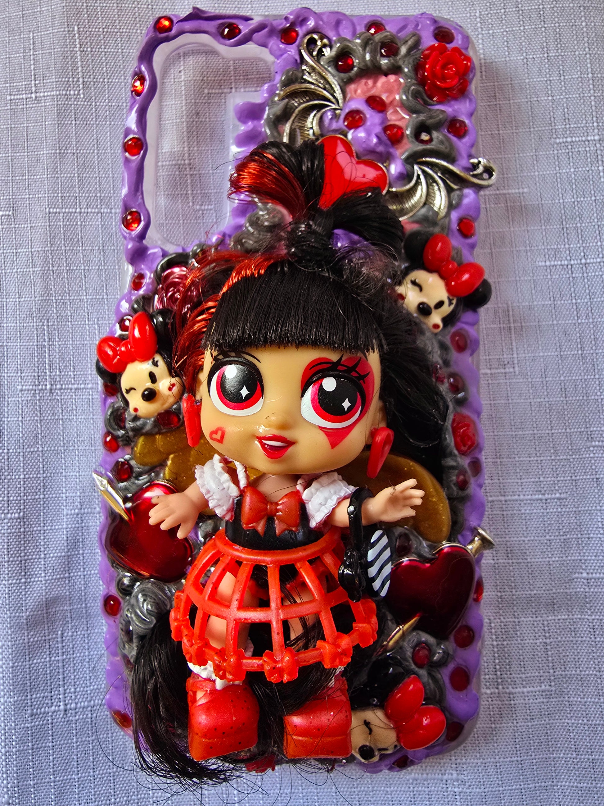 Handmade Samsung S23 Plus phone case with gothic and doll-inspired design, featuring red and black accents, heart charms, and 3D figure on a purple base.